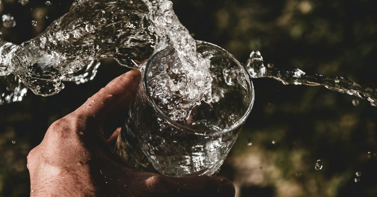 Una mano sostiene un vaso de agua transparente.