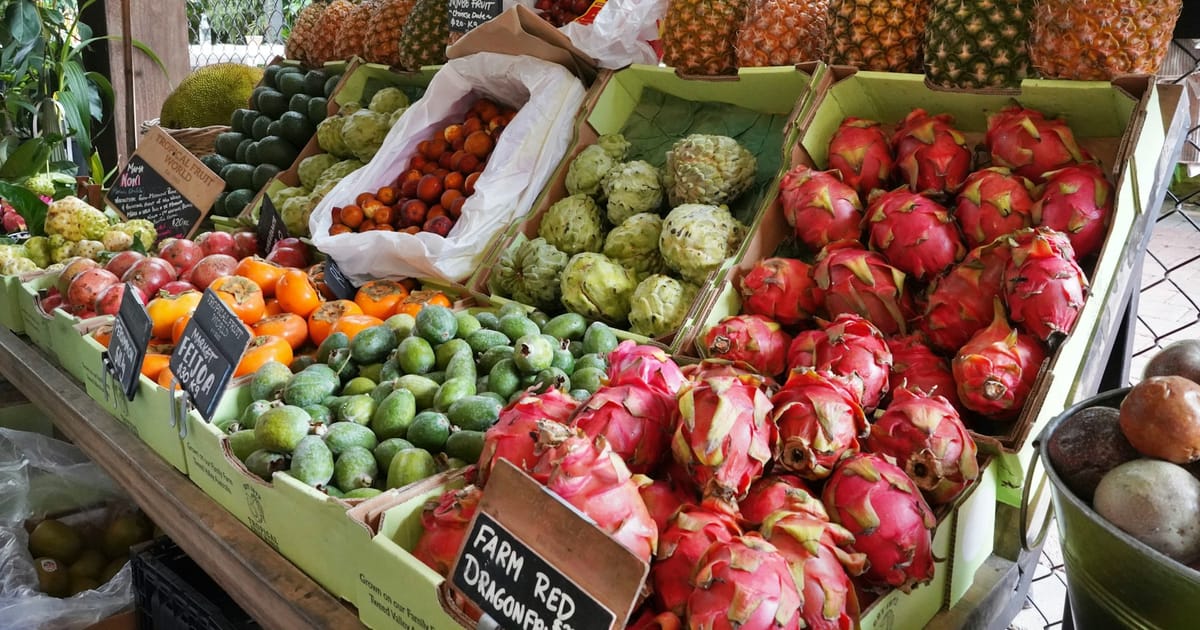 Puesto de mercado con frutas tropicales frescas apiladas.