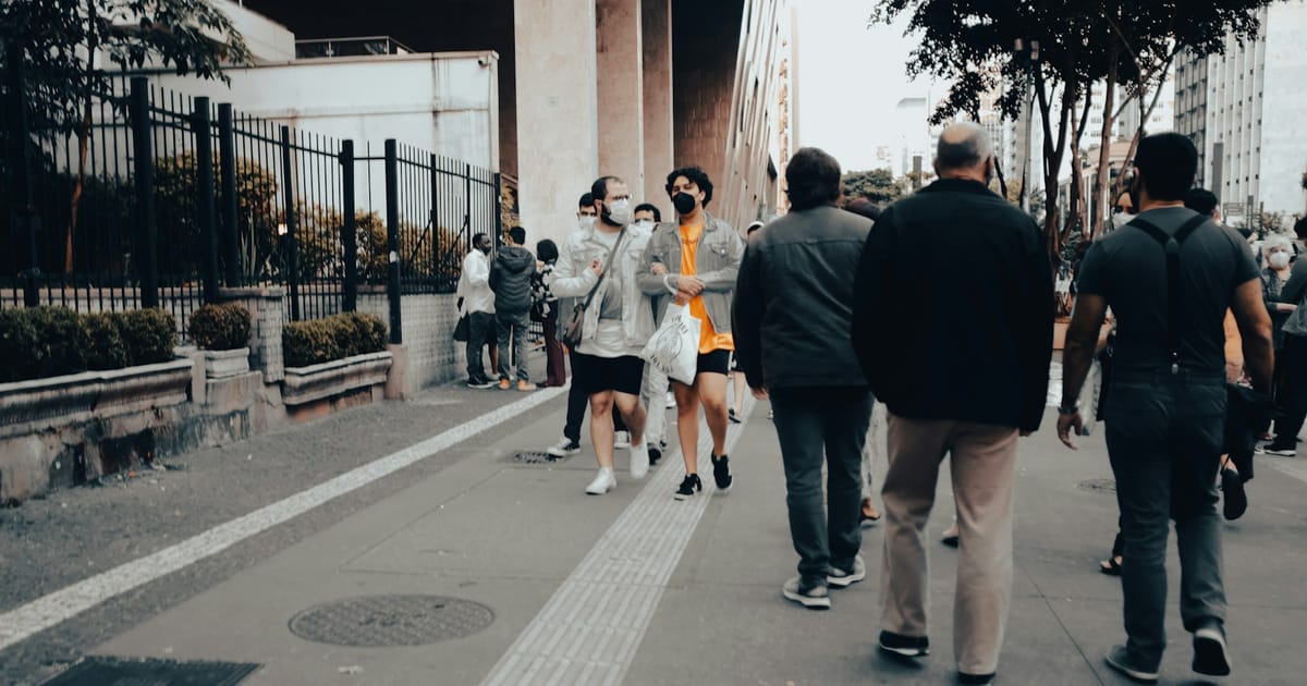 Un grupo de personas caminando por una acera en una calle de ciudad.
