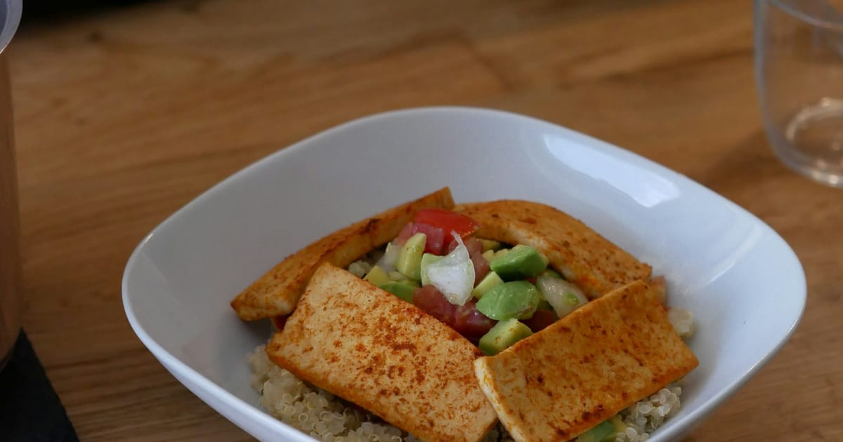 Un tazón de quinua con tofu, palta y verduras frescas.
