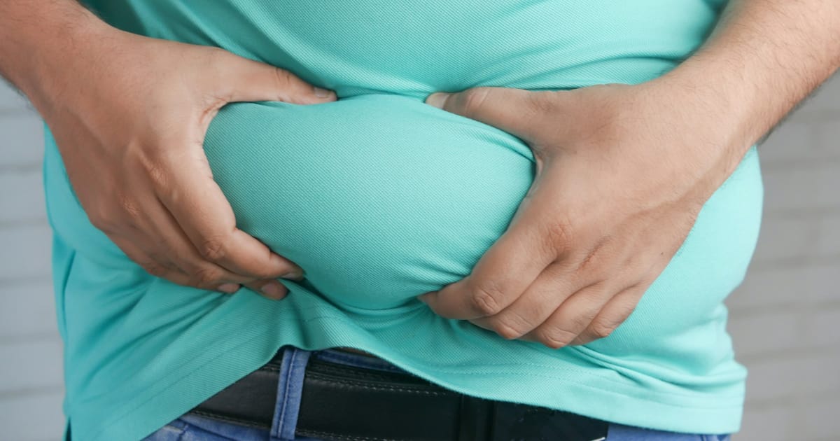 Una persona se sostiene el abdomen con las dos manos.