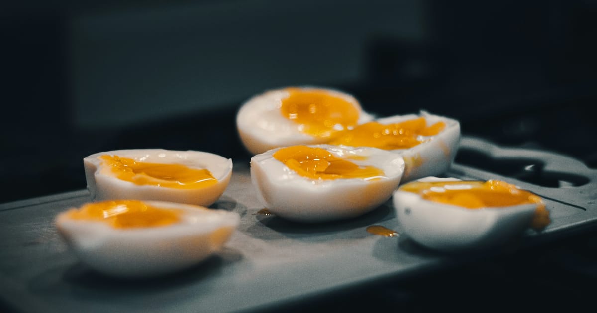 Varios huevos duros partidos por la mitad sobre una bandeja oscura.