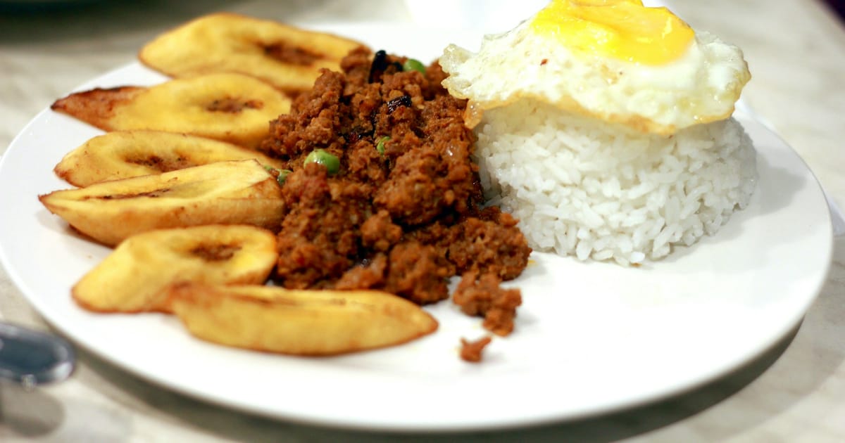 Un plato con arroz blanco, carne picada, plátano frito en rodajas y un huevo frito.