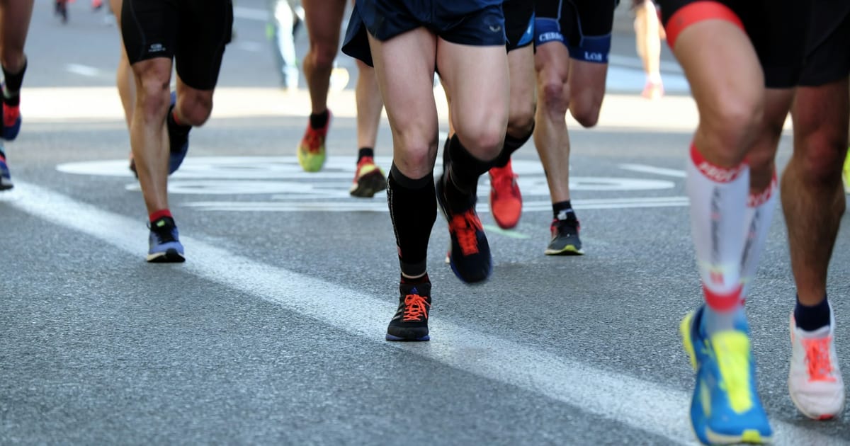 Personas corriendo sobre una calle asfaltada durante el día.