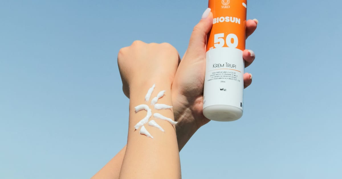 Una persona sostiene un frasco de protector solar en la mano.