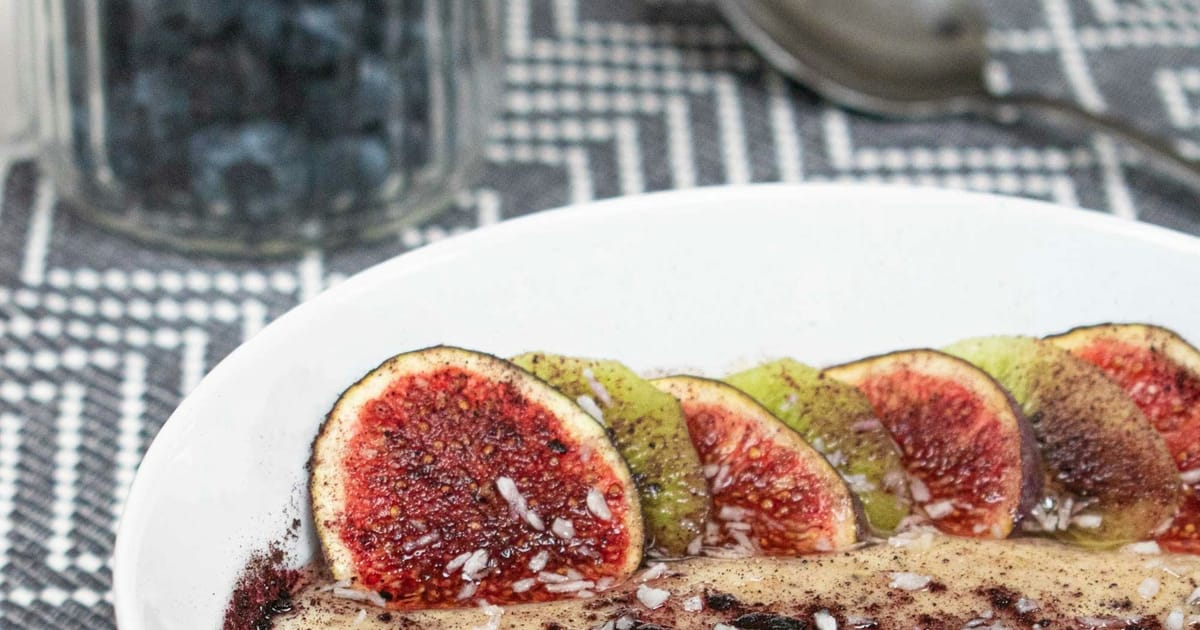 Un plato de grano cocido tipo papilla cubierto con higos y frutas en rodajas.