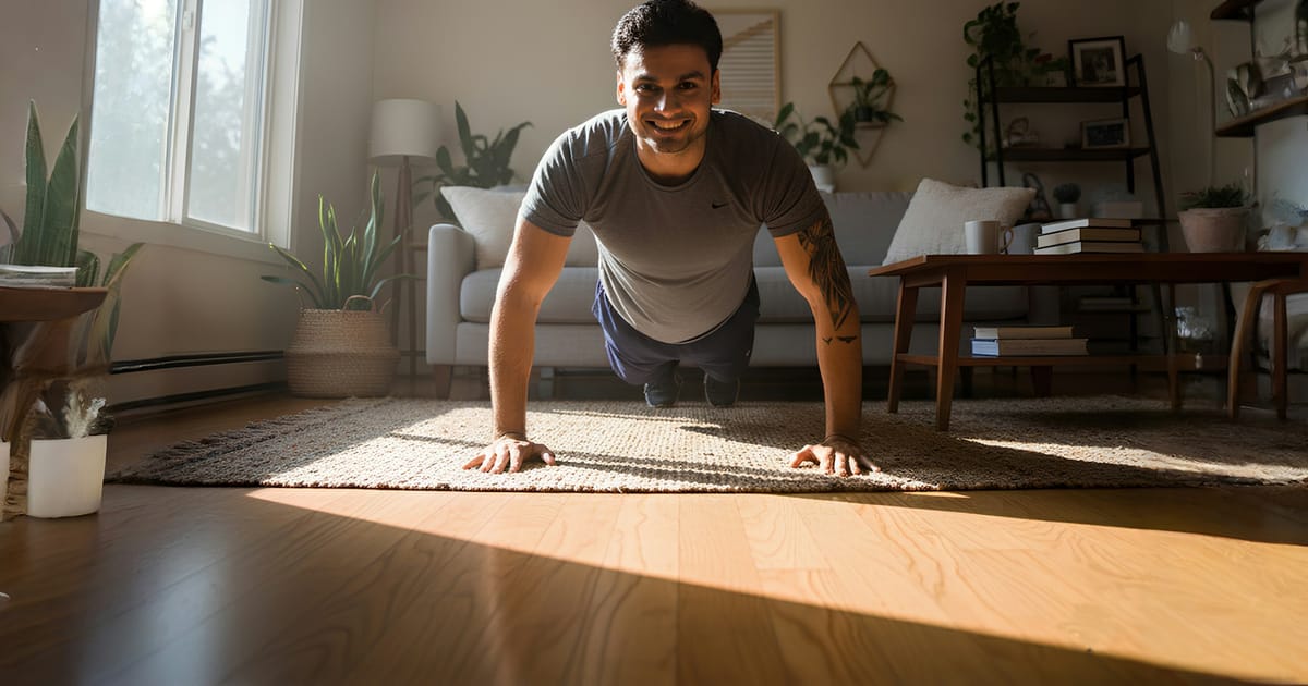 Un hombre hace flexiones de brazos en una sala iluminada por luz natural.