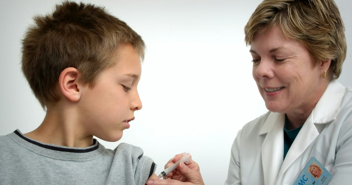 Una enfermera aplica una vacuna en el brazo de un niño.