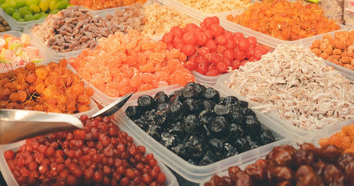 Variedad de frutas y frutos secos organizados en recipientes.