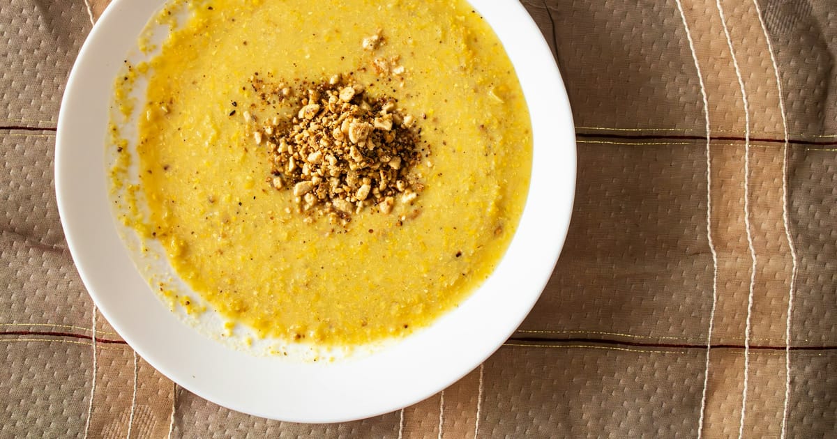 Un plato hondo con una sopa cremosa de color amarillo y maní picado encima.